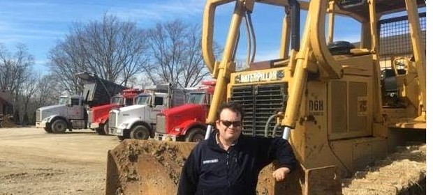 Colin Heidel on a site beside heavy equipment